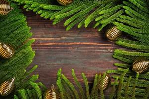 Hoja de pino de navidad con adornos dorados sobre mesa de madera