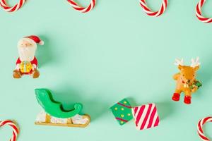 Juguete de navidad santa claus y renos vista superior con bastón de caramelo en la mesa verde pastel foto