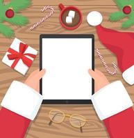 Santa holding tablet with his wooden table in the background, flat design illustration