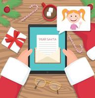 Santa claus is sitting at his workplace desk and receiving letter on his tablet from young girl - vector flat design illustration