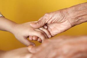 detail shot of child girl holding hand of a senior women photo