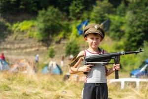 A little boy in his cap holds a trophy weapon MP-40 from the Second World War photo