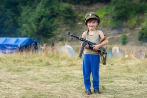 A little boy in his cap holds a trophy weapon MP-40 from the Second World War