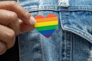 Asian lady holding rainbow color flag heart, symbol of LGBT pride month celebrate annual in June social of gay, lesbian, bisexual, transgender, human rights.