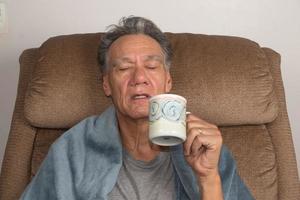 Mature Man not Feeling Well Wrap in a Blanket Drinking Tea photo