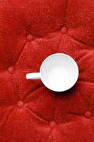 close up empty ceramic coffee cup on red sofa photo