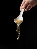 Spoon pouring noodle soup isolated on black background photo