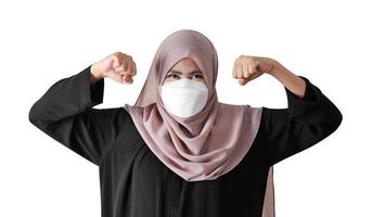 Muslim woman wearing surgical mask showing powerful arms on white background photo