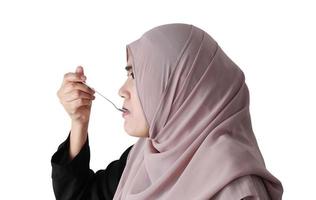 Muslim woman eating rice with spoon on white background. Healthy eating concept. photo