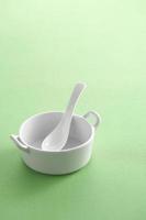 Taza de sopa blanca y cuchara blanca sobre fondo verde foto