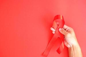 The red ribbon is an international sign of HIV and AIDS awareness, with individuals wearing red ribbons to show support for those who are living with the disease photo