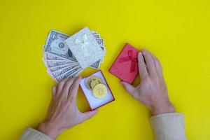 mano sostiene un regalo de año nuevo de dinero y bitcoin foto