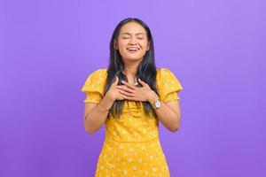 Beautiful young Asian woman put hands on chest on purple background photo