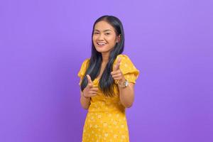 Portrait of cheerful young Asian woman pointing finger at camera on purple background photo