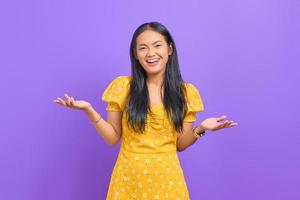 Retrato de mujer asiática joven emocionada celebrando el éxito sobre fondo púrpura foto