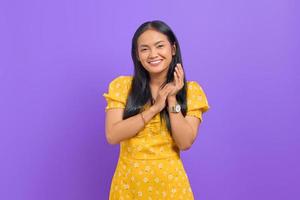 Smiling young Asian woman rub hands and looking at camera on purple background photo