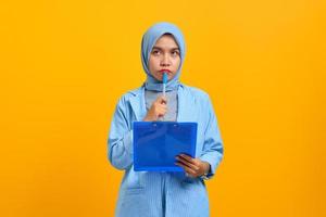 Young Asian woman concentrated writing notes planning creating strategy over yellow background photo