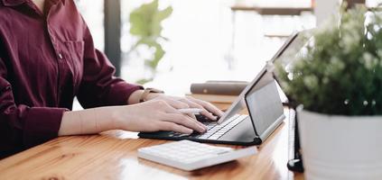 Close up Business woman using calculator and laptop for do math finance on wooden desk in office and business working background, tax, accounting, statistics and analytic research concept photo