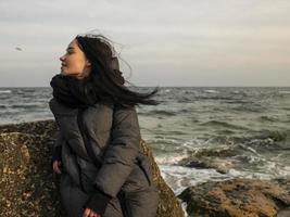 girl sitting on a stone near the sea photo