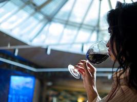 chica con hermosos labios que bebe vino tinto de una copa foto