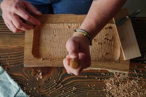 woodcarver processes a walnut wood board with a chisel photo