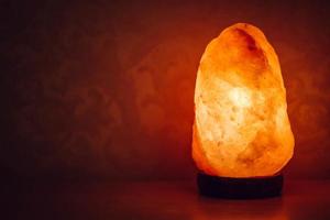Salt lamp on the table in the room glows in the night photo