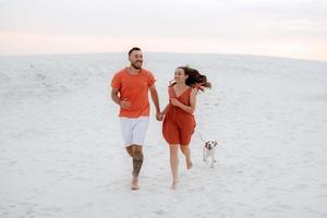 young couple in orange clothes with dog photo