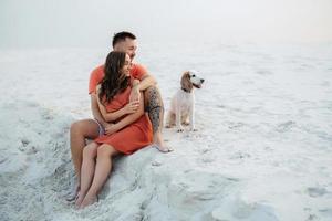 young couple in orange clothes with dog photo