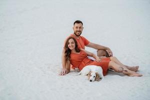 young couple in orange clothes with dog photo