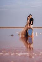 chica y chico en la orilla de un lago salado rosa