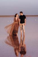 girl and a guy on the shore of a pink salt lake photo