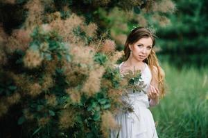 Happy girl in a turquoise long dress in a green park photo