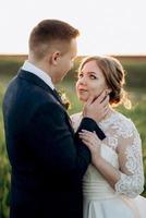 the groom and the bride walk along the wheat green field photo