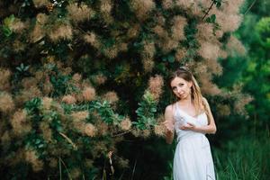 Happy girl in a turquoise long dress in a green park photo