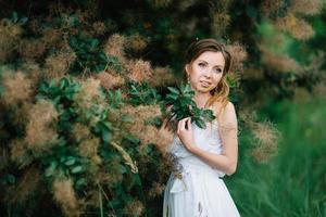 Happy girl in a turquoise long dress in a green park photo