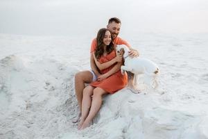 young couple in orange clothes with dog photo