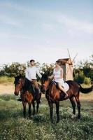 girl in a white sundress and a guy in a white shirt on a walk with brown horses photo