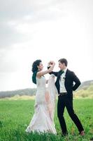 the groom in a brown suit and the bride in an ivory-colored dress on a green field photo