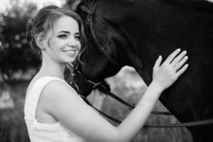 girl in a white sundress on a walk with brown horses photo