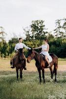 girl in a white sundress and a guy in a white shirt on a walk with brown horses photo