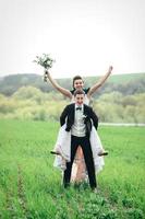 the groom in a brown suit and the bride in an ivory-colored dress on a green field photo