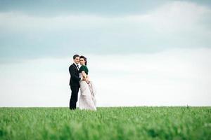 the groom in a brown suit and the bride in an ivory-colored dress on a green field photo