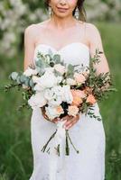 bride in a white dress with a large spring bouquet photo