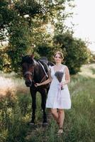 girl in a white sundress on a walk with brown horses photo