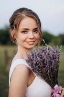 girl in a white sundress and a guy in a white shirt on a walk at sunset with a bouquet photo