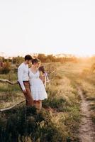 chica con un vestido blanco y un chico con una camisa blanca en un paseo al atardecer con un ramo foto