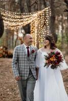 walk of the bride and groom through the autumn forest photo