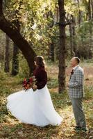 walk of the bride and groom through the autumn forest photo