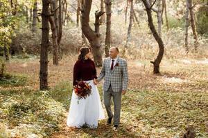 walk of the bride and groom through the autumn forest photo