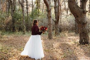 girl in a wedding dress in the autumn forest photo